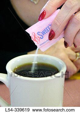 Stock Photograph - woman pours artificial 
sweetener in a 
cup of coffee. 
fotosearch - search 
stock photos, 
pictures, images, 
and photo clipart