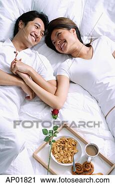Stock Photography - couple lying on 
bed, holding hands, 
breakfast on tray 
next to them. 
fotosearch - search 
stock photos, 
pictures, images, 
and photo clipart