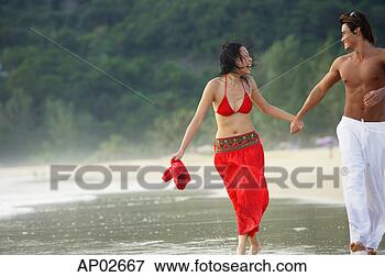 Picture - couple running 
along beach, ankle 
deep in water, 
holding hands. 
fotosearch - search 
stock photos, 
pictures, images, 
and photo clipart