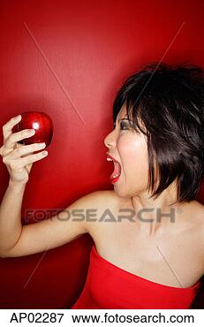 Picture - woman in red tube 
tope holding red 
apple, mouth open. 
fotosearch - search 
stock photos, 
pictures, images, 
and photo clipart