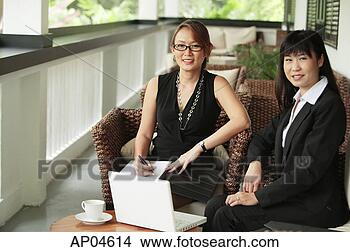 Stock Photo - two businesswomen 
sitting on patio 
with laptop, looking 
at camera. fotosearch 
- search stock 
photos, pictures, 
images, and photo 
clipart