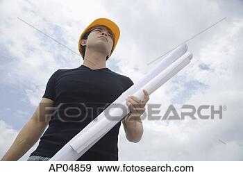 Stock Photograph - young man wearing 
hardhat, carrying 
blueprints, low 
angle view. fotosearch 
- search stock 
photos, pictures, 
images, and photo 
clipart