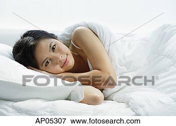 Picture - young woman lying 
on bed, looking 
at camera. fotosearch 
- search stock 
photos, pictures, 
images, and photo 
clipart