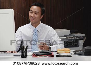 Stock Photo - a man has a hot 
drink while he 
works at his desk. 
fotosearch - search 
stock photos, 
pictures, images, 
and photo clipart