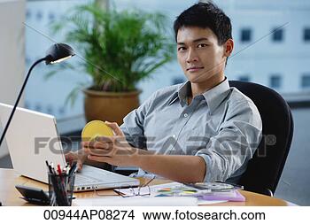 Stock Photo - a man looks at 
the camera as 
he sits at his 
desk. fotosearch 
- search stock 
photos, pictures, 
images, and photo 
clipart