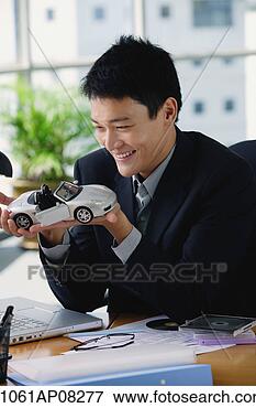 Picture - a man plays with 
a toy car on his 
desk. fotosearch 
- search stock 
photos, pictures, 
images, and photo 
clipart