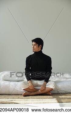 Stock Photo - young man sitting 
on bed, looking 
sideways. fotosearch 
- search stock 
photos, pictures, 
images, and photo 
clipart