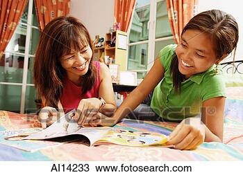 Stock Photo - mother with daughter, 
lying on bed, 
looking at magazine. 
fotosearch - search 
stock photos, 
pictures, images, 
and photo clipart