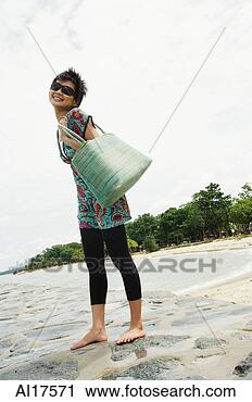 Stock Photography - woman standing 
on beach, carrying 
beach bag. fotosearch 
- search stock 
photos, pictures, 
images, and photo 
clipart