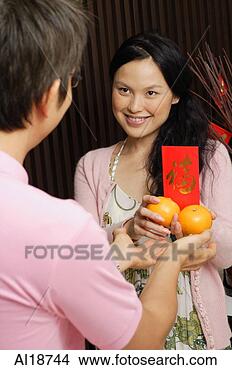 Stock Photo - couple standing 
face to face, 
exchanging oranges 
and red packet. 
fotosearch - search 
stock photos, 
pictures, images, 
and photo clipart