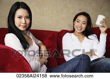 Stock Photo - two woman on couch, 
one with cup in 
hand. fotosearch 
- search stock 
photos, pictures, 
images, and photo 
clipart