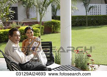 Stock Photo - couple sitting 
outside, holding 
photograph, woman 
in sari and bindi. 
fotosearch - search 
stock photos, 
pictures, images, 
and photo clipart