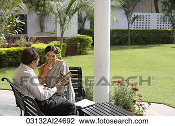 Stock Photo - couple sitting 
outside, holding 
photograph, woman 
in sari and bindi. 
fotosearch - search 
stock photos, 
pictures, images, 
and photo clipart