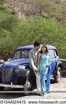 Stock Image - young couple looking 
at each other 
in front of blue 
antique car. fotosearch 
- search stock 
photos, pictures, 
images, and photo 
clipart