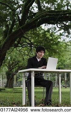 Stock Photo - young man in suit, 
using laptop at 
a park. fotosearch 
- search stock 
photos, pictures, 
images, and photo 
clipart