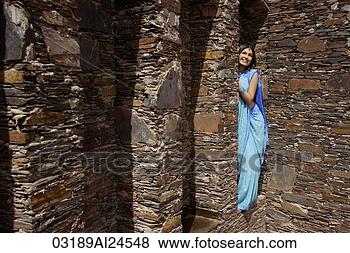 Stock Photo - young woman in 
sari, peeking 
from behind brick 
pillar. fotosearch 
- search stock 
photos, pictures, 
images, and photo 
clipart