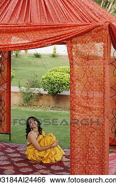 Stock Photo - young woman in 
yellow sari, sitting 
in red tent. fotosearch 
- search stock 
photos, pictures, 
images, and photo 
clipart