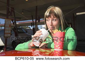 Stock Image - closeup of coy 
woman eating at 
drive-in. fotosearch 
- search stock 
photos, pictures, 
images, and photo 
clipart