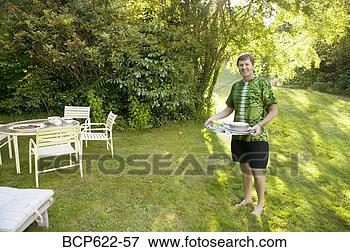 Picture - man carrying tray 
to table in yard. 
fotosearch - search 
stock photos, 
pictures, images, 
and photo clipart