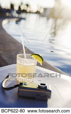 Stock Photography - margarita and 
camera on poolside 
table. fotosearch 
- search stock 
photos, pictures, 
images, and photo 
clipart