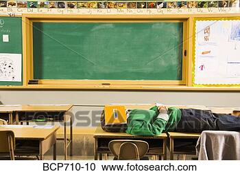 Stock Photography - boy laying on 
classroom desks 
with book over 
face. fotosearch 
- search stock 
photos, pictures, 
images, and photo 
clipart