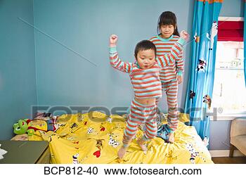 Stock Photography - asian siblings 
jumping on bed. 
fotosearch - search 
stock photos, 
pictures, images, 
and photo clipart