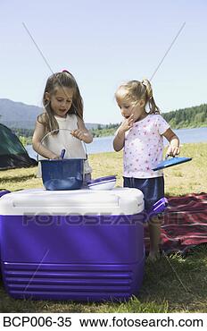 Stock Image - young sisters 
preparing food 
on a cooler at 
a campsite. fotosearch 
- search stock 
photos, pictures, 
images, and photo 
clipart