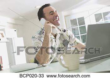 Stock Photo - man talking on 
the phone and 
working on a laptop. 
fotosearch - search 
stock photos, 
pictures, images, 
and photo clipart