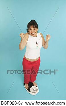 Picture - a happy woman 
standing on a 
scale. fotosearch 
- search stock 
photos, pictures, 
images, and photo 
clipart
