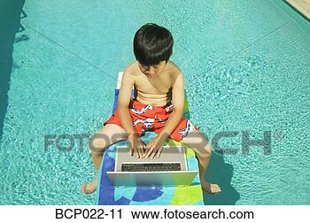 Stock Photography - youngster working 
on his laptop 
at poolside. fotosearch 
- search stock 
photos, pictures, 
images, and photo 
clipart