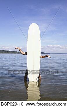 Stock Photography - man standing behind 
a surfboard. fotosearch 
- search stock 
photos, pictures, 
images, and photo 
clipart
