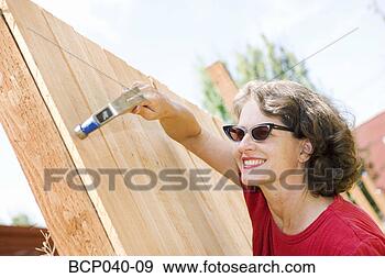 Stock Photograph - woman hammering 
wooden fence. 
fotosearch - search 
stock photos, 
pictures, images, 
and photo clipart