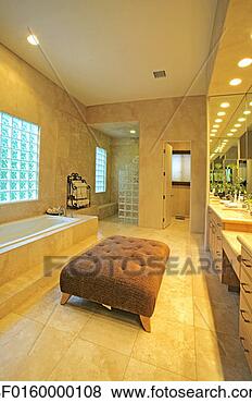 Stock Photo - a tufted, upholstered 
ottoman provides 
seating in a master 
bathroom. fotosearch 
- search stock 
photos, pictures, 
images, and photo 
clipart