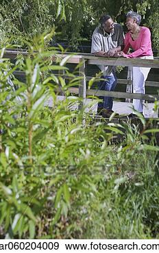 Stock Photograph - elderly couple 
standing together 
leaning on a wooden 
railing in a park. 
fotosearch - search 
stock photos, 
pictures, images, 
and photo clipart