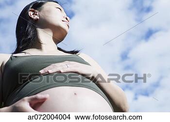 Stock Photo - low angle view 
of a pregnant 
woman holding 
her stomach. fotosearch 
- search stock 
photos, pictures, 
images, and photo 
clipart