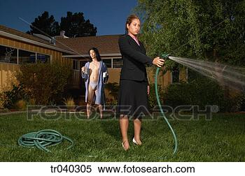 Stock Image - young woman watering 
the lawn with 
a hose. fotosearch 
- search stock 
photos, pictures, 
images, and photo 
clipart