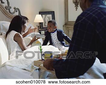 Stock Photo - woman lying in 
bed talking to 
a young boy with 
a man holding 
serving. fotosearch 
- search stock 
photos, pictures, 
images, and photo 
clipart