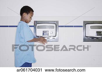 Stock Photography - young boy drying 
his hands under 
a hand blow dryer 
in the wash room. 
fotosearch - search 
stock photos, 
pictures, images, 
and photo clipart