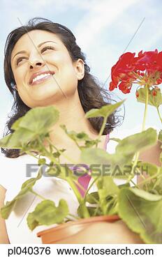 Stock Photo - low angle view 
of young woman 
holding a potted 
plant. fotosearch 
- search stock 
photos, pictures, 
images, and photo 
clipart