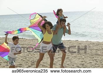 Stock Image - young couple and 
their children 
running on the 
beach with kites. 
fotosearch - search 
stock photos, 
pictures, images, 
and photo clipart