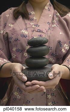 Stock Photo - young woman holding 
a pile of black 
stones. fotosearch 
- search stock 
photos, pictures, 
images, and photo 
clipart