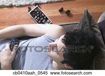 Stock Image - high angle view 
of a young man 
lying on couch 
holding a television. 
fotosearch - search 
stock photos, 
pictures, images, 
and photo clipart
