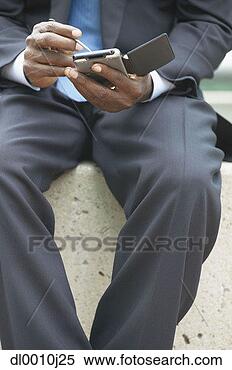 Stock Image - mid section view 
of mid adult businessman 
operating a hand 
held device. fotosearch 
- search stock 
photos, pictures, 
images, and photo 
clipart