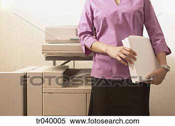 Stock Image - torso of a  businesswoman 
standing by a 
copying machine 
holding paper. 
fotosearch - search 
stock photos, 
pictures, images, 
and photo clipart