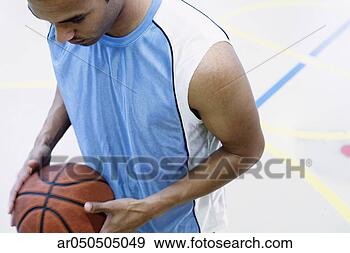 Stock Photograph - high angle view 
of a young man 
holding a basketball. 
fotosearch - search 
stock photos, 
pictures, images, 
and photo clipart