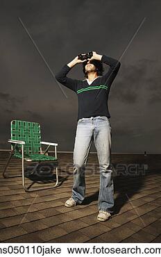 Stock Photography - low angle view 
of a young man 
looking through 
binoculars. fotosearch 
- search stock 
photos, pictures, 
images, and photo 
clipart
