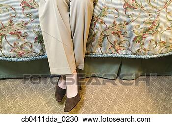 Stock Photography - low section view 
of a mid adult 
woman sitting 
on a bed. fotosearch 
- search stock 
photos, pictures, 
images, and photo 
clipart
