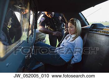 Stock Photography - mid adult woman 
arrested by a 
police officer 
sitting in a police 
car. fotosearch 
- search stock 
photos, pictures, 
images, and photo 
clipart