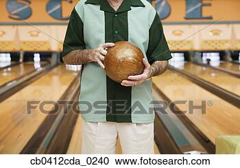 Stock Photography - mid section view 
of a mid adult 
man holding a 
bowling ball in 
a. fotosearch 
- search stock 
photos, pictures, 
images, and photo 
clipart