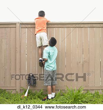 Stock Photo - rear view of a 
boy helping another 
boy climbing a 
fence. fotosearch 
- search stock 
photos, pictures, 
images, and photo 
clipart